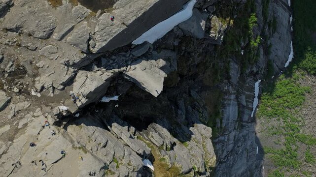 Rocky cliffs with snow patches at Trolltunga in Norway. Aerial drone view of rugged stone textures and melting snow in the high mountains on a sunny summer day.