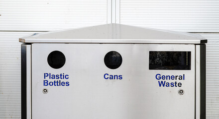 Recycling station with labeled bins for plastic bottles, cans, and general waste