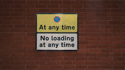 Fototapeta premium No loading sign on brick wall indicating parking restrictions at any time