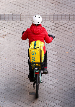 Delivey de Glovo rider en bicicleta llevando un pedido a domicilio de comida
