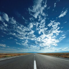 Empty road stretching to horizon under a brilliant, cloudy sky