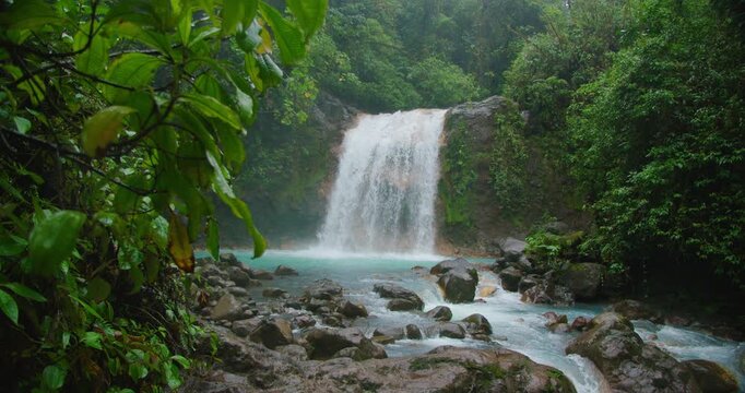 Scenic waterfall cascading into a turquoise pool surrounded by lush Costa Rica rainforest