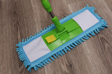 Green plastic mop with rag on the floor