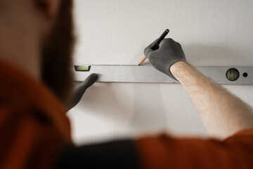 Close-up of man with spirit level measuring wall. repair, building and home concept