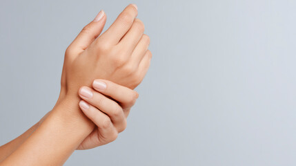 A light-skinned person gently holds their left wrist with their right hand.