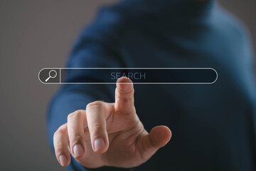 Hand touching digital search bar with magnifying glass icon. Concept of online search, search...