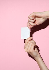 Obraz premium Hand holding Blank white sachet packet mockup on pink background. Empty disposable shampoo or conditioner pack mock up for your design
