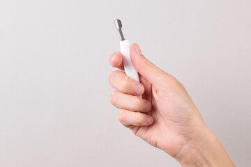 Hand holding manicure or pedicure tool on gray background