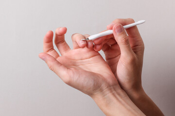 Woman's hand trims the cuticles on her finger using a manicure tool. Nail care