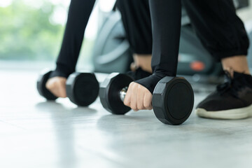 Close-up of woman hands gripping black dumbbells on gym floor, ready for strength training. Symbolizes power, focus, fitness commitment. Great for workout, health and active lifestyle themes.