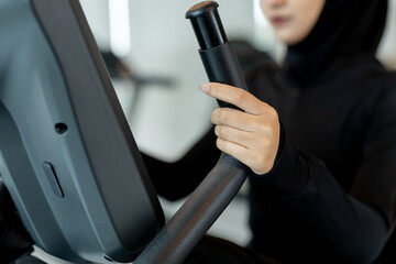 Close-up of women hand holding elliptical machine handle during cardio workout at gym. Promotes healthy lifestyle, fitness routine, exercise motivation, modern indoor training equipment.