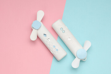 Handheld electronic fans on blue pink pastel background