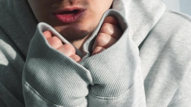 A freezing man in a long-sleeved sweater.
A warmly dressed man warms himself in low temperatures.