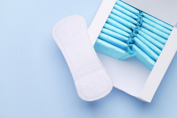 Box with sanitary pads on blue background. Feminine hygiene © splitov27