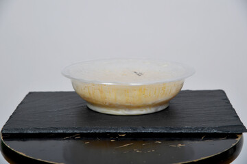 Schlichte Schüssel mit Nudeln und heller Sauce auf dunkler Unterlage vor neutralem Hintergrund....