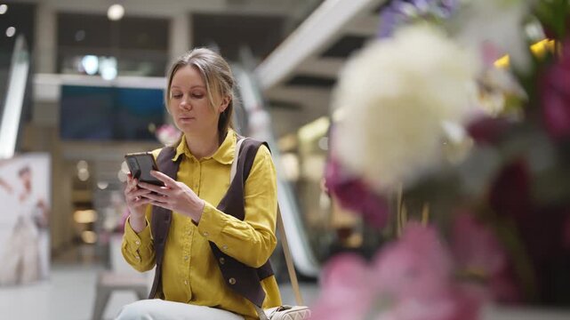 Woman using smartphone in modern shopping mall.