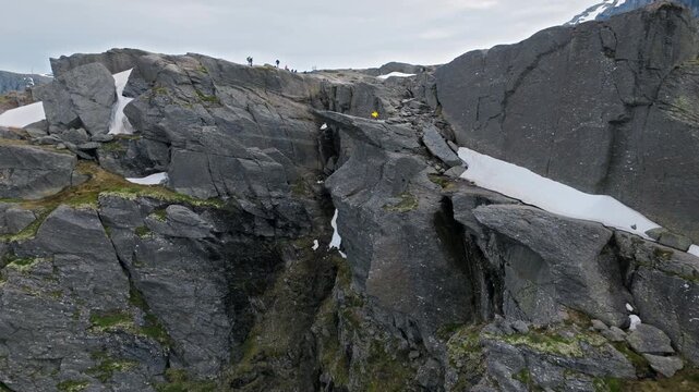 Rock formations and narrow crevice near Trolltunga hiking area in Norway. Rugged mountain terrain with patches of snow showing extreme alpine conditions.