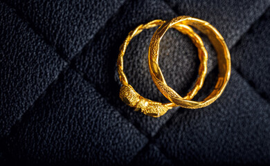 Pair of Gold Twisted Rings on dark textured Background, Top view, wedding bands, couple rings