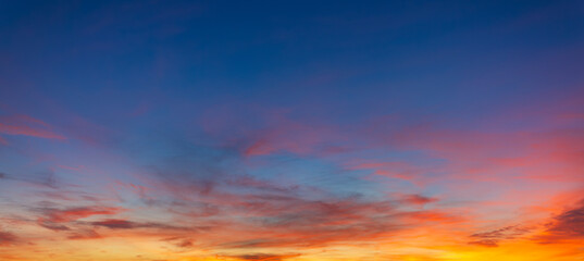 Fototapeta premium Vibrant Panoramic Sunset Sky with Dramatic Pink and Orange Clouds,A breathtaking panoramic view of a sunset sky featuring a vivid transition from deep blue to brilliant orange and pink hues,