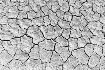 Parched and Cracked Dry Earth Texture in Black and White,High-contrast black and white photograph of dry, cracked mud on a barren landscape. The intricate network of deep fissures highlights severe,