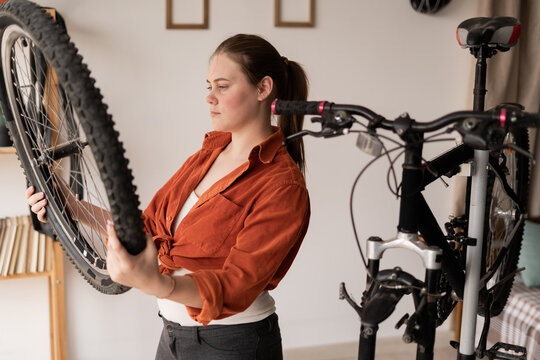Focused bicycle mechanic repairing bike wheel at home - Powered by Adobe