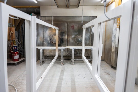 Vue de cadres menuiseries aluminium de vitres blancs dispos&eacute;s en atelier, illustrant un environnement de fabrication ou de pr&eacute;paration de menuiseries avec un aspect industriel et organis&eacute;.