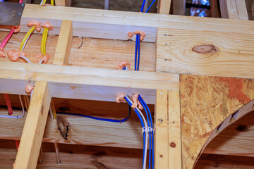 Construction work showing electrical, plumbing installations in wooden beams at building site