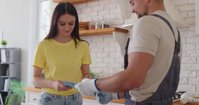 Plumber and client finalize kitchen plumbing service. They review the estimate after drain clog repair and sign the contract. Professional customer trust, maintenance and repair service.oncept.