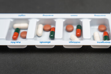 Close-up of a weekly pill organizer with capsules and tablets sorted by day. Medical concept of...