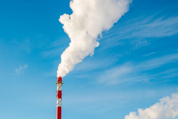 white smoke from a red chimney against a blue sky