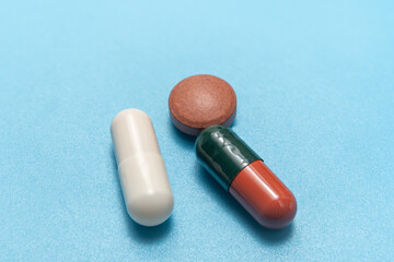 Capsules and a tablet isolated on a blue background. Clean pharmaceutical concept for medicine,...