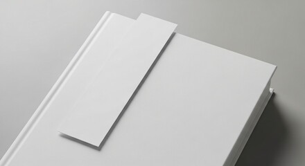 Closeup view of a blank white book with a bookmark, resting on a light grey surface, ideal for mockups and branding