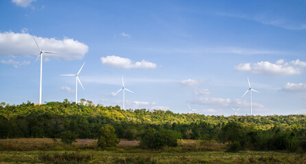 Wind turbines farm on green mountain range under blue sky, Renewable energy concept.