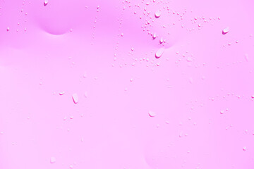 Pink water bubbles on the surface ripples. Defocus blurred transparent pink colored clear calm water surface texture with splash and bubbles. Water waves with shining pattern texture background