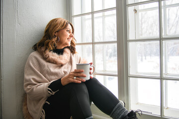Portrait of mature woman inside on the window side drink coffee