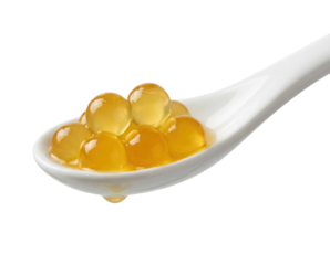 A white spoon holds several glossy, round, golden spheres that resemble caviar or gelatin, creating an appealing and luxurious presentation.