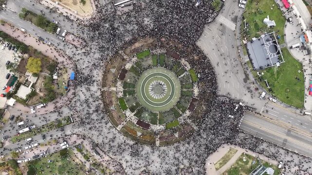 An aerial view of thousands of Syrians celebrating the end of the war in Damascus, carrying Syrian flags