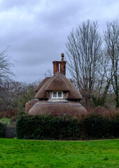 A quaint thatched-roof cottage nestled in a green landscape.