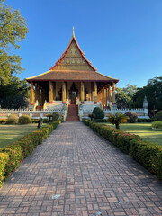 Haw Phra Kaew temple in Vientiane, Laos, featuring traditional Lao architecture, golden details, and a peaceful garden under clear blue sky.