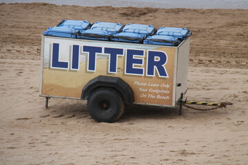 Some Litter Wheelie Bins in a Trailer on a Seaside Beach.