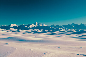winter snow landscape with white dunes and mountain range under blue sky