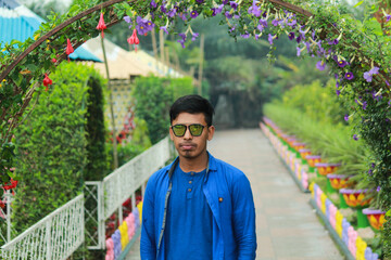 Young Man in Sunglasses Posing in a Flower Garden  Outdoor Portrait