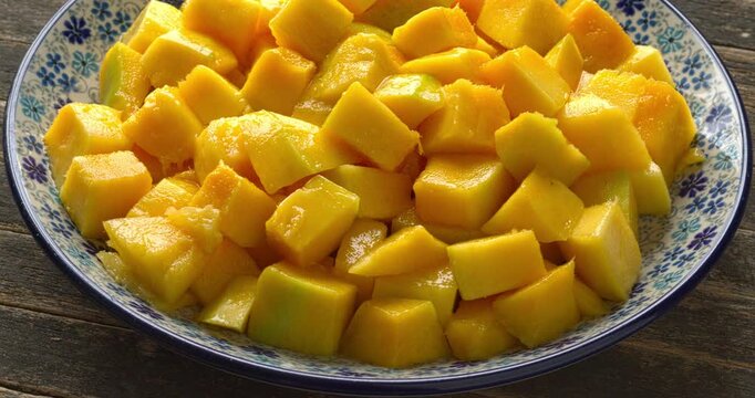 A rotating plate with diced ripe mango pieces on rustic boards.