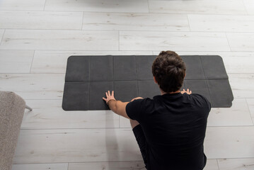 Man laying out yoga mat for fitness, top-down view