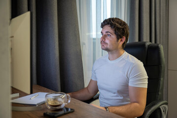 Focused worker at home workstation with computer and cup