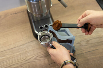 A man's hand pours coffee into a portafilter