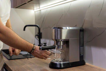 A silver espresso machine with a double-walled glass cup