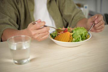 Close up of senior woman hands eating pumpkin salad with beans and drinking water. Elderly healthy lifestyle, organic nutrition, weight loss, and balanced diet concept for wellness.