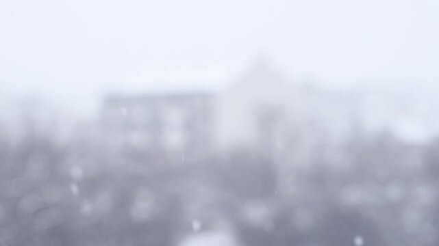 4K blurred snowfall with out of focus buildings in heavy winter whiteout