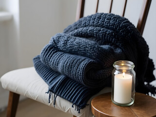 A candle is lit on a table next to a blue blanket